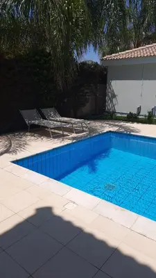 a blue swimming pool with a chair next to a house at ANTHORINA VILLA 9 in Protaras