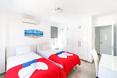 two beds in a white room with red sheets at Beach Front Aqua Marina by Ezoria Villas in Paralimni
