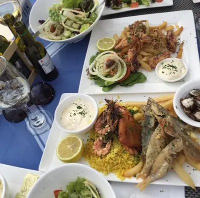 a table topped with plates of food with fish and rice at Palma Villa 14 in Protaras