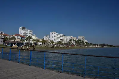 a boardwalk next to a body of water with buildings at Kolonaki Seaview Apartments in Larnaka