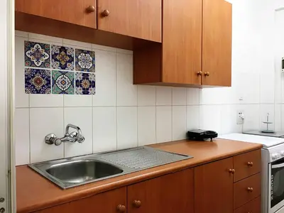 a kitchen with a sink and wooden cabinets at Comfortable Engomi Apartment in Yukarı Lakatamya