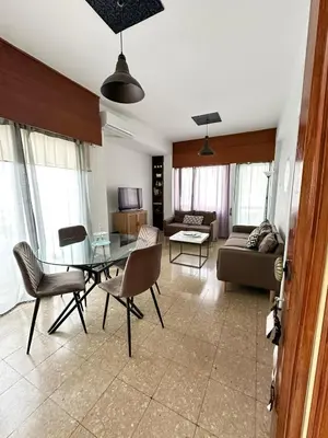 a living room with a glass table and chairs at Comfortable Engomi Apartment in Yukarı Lakatamya