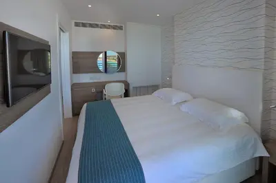 a bedroom with a white bed and a television at Okeanos Beach Boutique Hotel in Ayia Napa