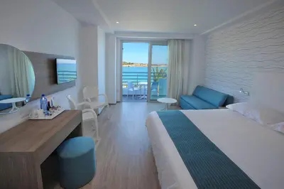 a hotel room with a bed and a dining room at Okeanos Beach Boutique Hotel in Ayia Napa