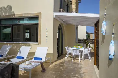 a patio with white chairs and a table on a balcony at Villa Mylos 8 in Protaras