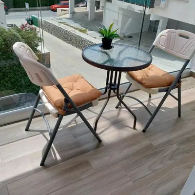a glass table and two chairs on a patio at Chicos Studios in Ayia Napa