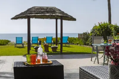 a table with a straw umbrella on a patio at Meneou Beachfront Villa in Meneou