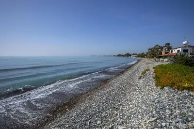a rocky beach with a house and the ocean at Meneou Beachfront Villa in Meneou