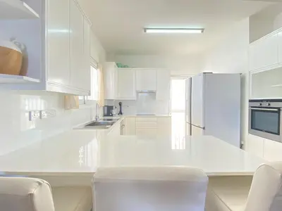 a white kitchen with white appliances and white cabinets at Phaedrus Living: Seaside Luxury Villa Anafi in Paralimni
