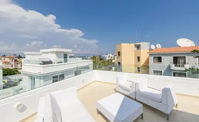 a balcony with white furniture and a view of the city at Green Bay Villa #13 in Protaras