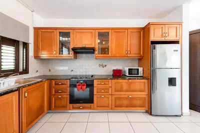 a kitchen with wooden cabinets and a white refrigerator at Sea Front Costa Blu by Ezoria Villas in Ayia Napa