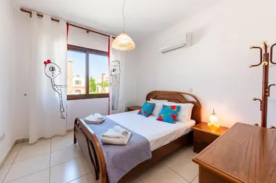 a bedroom with a bed and a table and a window at Sea Front Costa Blu by Ezoria Villas in Ayia Napa