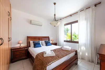 a bedroom with a bed with blue pillows and a window at Sea Front Costa Blu by Ezoria Villas in Ayia Napa