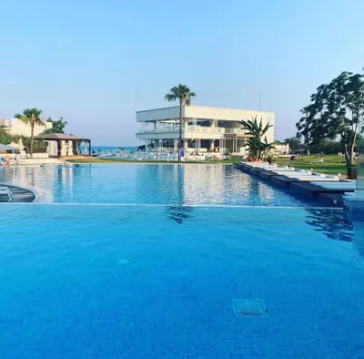 a large pool of blue water in front of a building at So White Beach Resort in Ayia Napa