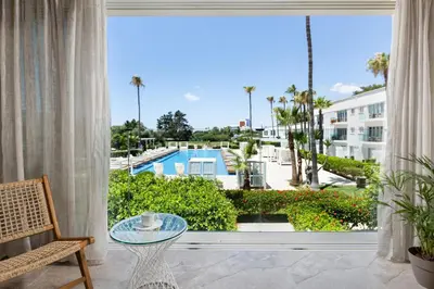 a room with a large window with a view of a pool at So White Beach Resort in Ayia Napa