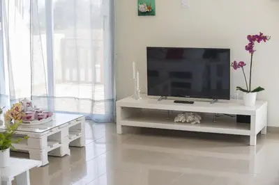 a living room with a television on a white entertainment center at Protaras Galleria Sunset Villa in Paralimni