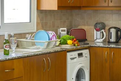 a kitchen with a washing machine and vegetables on the counter at Protaras Galleria Sunset Villa in Paralimni