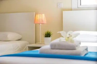 a bedroom with two beds and a table with a lamp at Protaras Galleria Sunset Villa in Paralimni