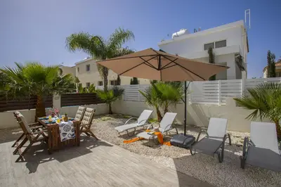 a patio with a table and an umbrella at Protaras Galleria Sunset Villa in Paralimni