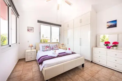 a bedroom with a bed with white cabinets and windows at Villa Willow Mandali by Ezoria Villas in Protaras