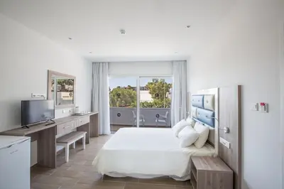 a bedroom with a bed and a desk and a television at Stratovarius Nissi Rooms in Ayia Napa