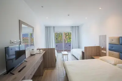 a hotel room with a television and a bedroom at Stratovarius Nissi Rooms in Ayia Napa