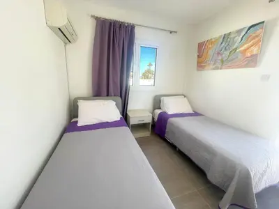 two beds in a small room with a window at Christina Apartment in Protaras