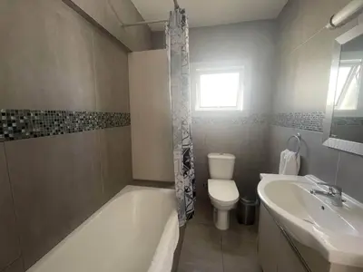 a bathroom with a tub and a toilet and a sink at Christina Apartment in Protaras
