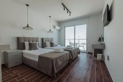 a bedroom with two beds and a large window at River View Boutique Apts in Ayia Napa