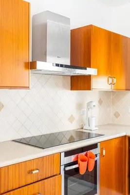 a kitchen with wooden cabinets and a stove top oven at Sea Front Oceanus H2 by Ezoria Villas in Ayia Napa