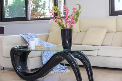 a glass table with a vase with flowers on it at Konnos Blue in Protaras