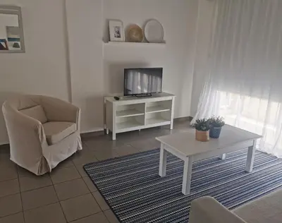 a living room with a tv and a chair and a table at Nostalgia apts in Limassol