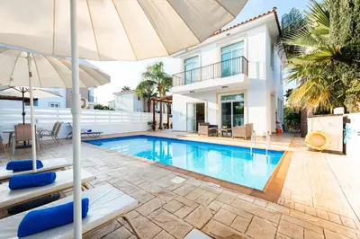 a villa with a swimming pool and an umbrella at Villa Palm Breeze by Ezoria Villas in Protaras