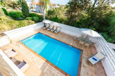 an overhead view of a swimming pool with chairs and an umbrella at Villa Palm Breeze by Ezoria Villas in Protaras