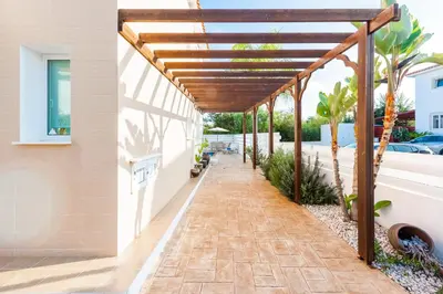 a patio with a wooden pergola on a house at Villa Palm Breeze by Ezoria Villas in Protaras