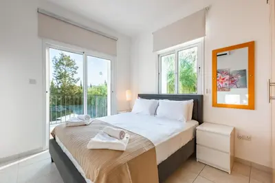 a bedroom with a large bed and windows at Villa Palm Breeze by Ezoria Villas in Protaras