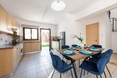 a kitchen and dining room with a wooden table and chairs at Villa Iris by Ezoria Villas in Ayia Napa