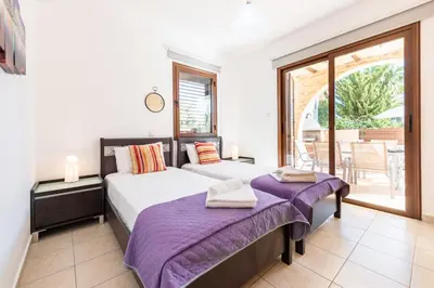 a bedroom with two beds and a balcony at Villa Iris by Ezoria Villas in Ayia Napa