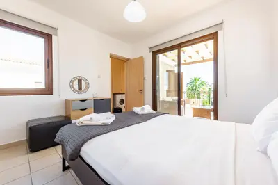 a bedroom with a large white bed and a window at Villa Iris by Ezoria Villas in Ayia Napa