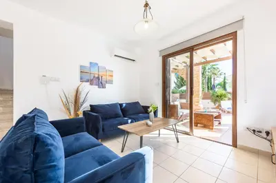 a living room with a blue couch and a table at Villa Iris by Ezoria Villas in Ayia Napa