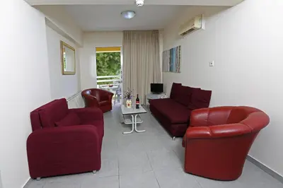 a living room with two red chairs and a table at Sunquest Gardens Holiday Resort in Limassol