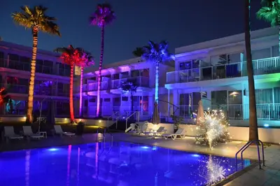 a hotel with a pool and palm trees at night at Lysithea Hotel in Larnaka