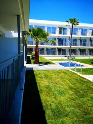 a large building with palm trees in front of a yard at Lysithea Hotel in Larnaka