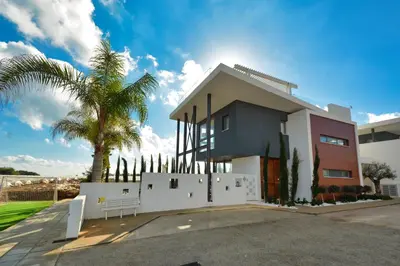 a house with a white fence and a palm tree at White Pearl Villas in Protaras