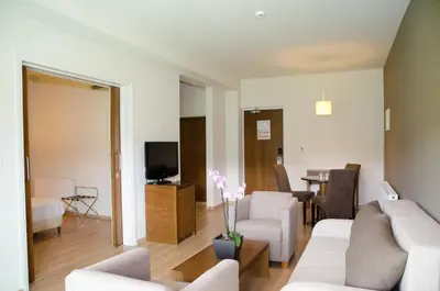 a living room with white furniture and a tv at Rodon Hotel and Resort in Agros
