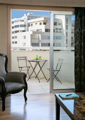 a room with a balcony with a chair and a table at Cleopatra Hotel in Nicosia