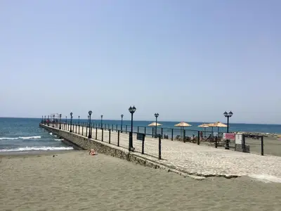 a beach with a pier with umbrellas and the ocean at Modern Seaview Beach Studio Limassol in Limassol