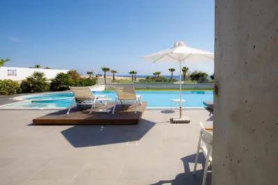 a swimming pool with two chairs and an umbrella at Beachfront Luxury Villa Tranquility in Ayia Napa
