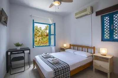 a bedroom with a bed and two tables and a window at Protaras Ayios Elias Suite in Protaras