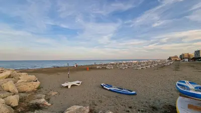 a beach with chairs and umbrellas and boats on it at Serenity by the sea in Larnaka